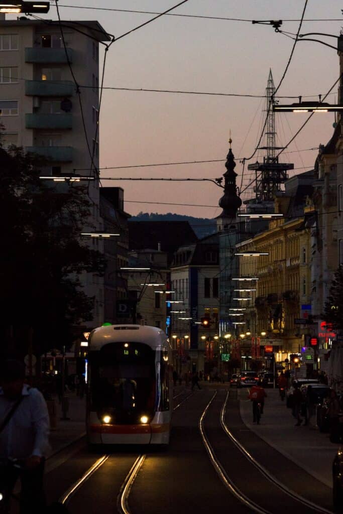 a city street at night with a tram on the tracks